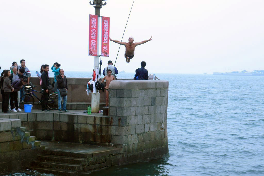 прыгающий в воду человек на пляже в Циндао